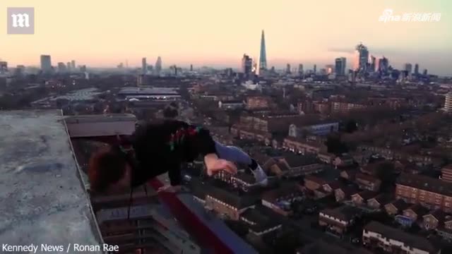 视频：小伙登上摩天大楼顶端 单手悬挂大楼边缘拍视
