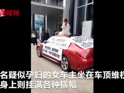 视频：广东疑有孕妇坐奔驰车顶维权 现场有人打伞保护